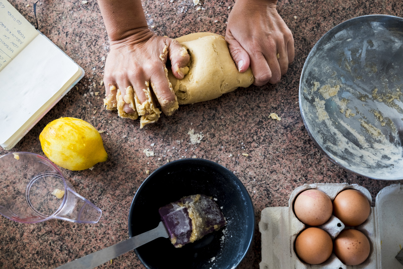 A pair of woman strong hands doing pasta for a cake in the kitchen. Eggs and lemon. Taken from above with different point of view